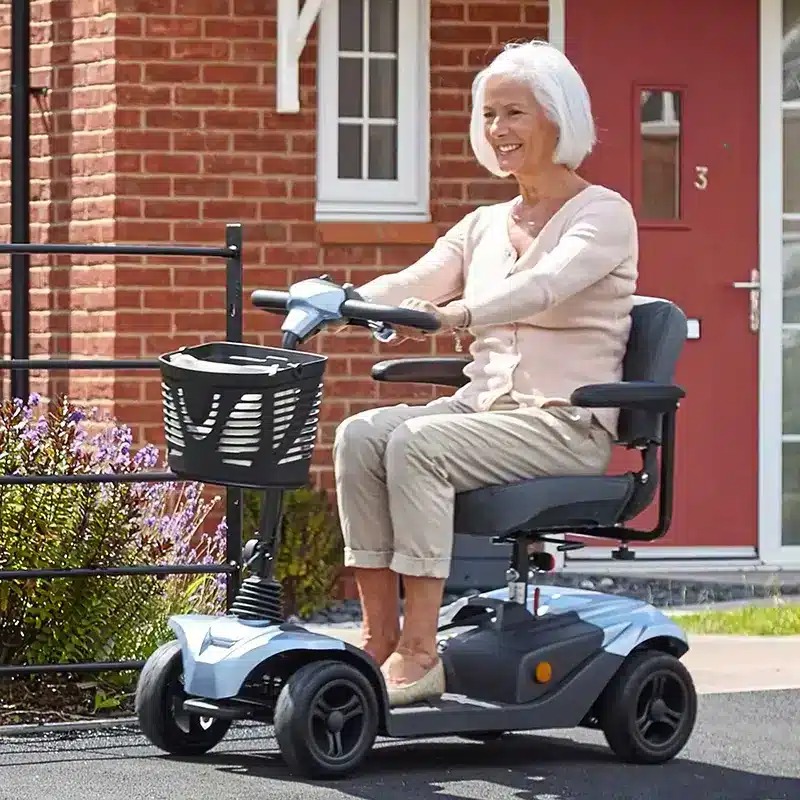 Foldable red-and-black travel mobility scooter on white background, showing handlebars, seat and carry bag.